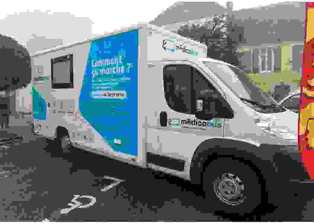 Un camion sur lequel est écrit medicobus est garé sur la place d'un village