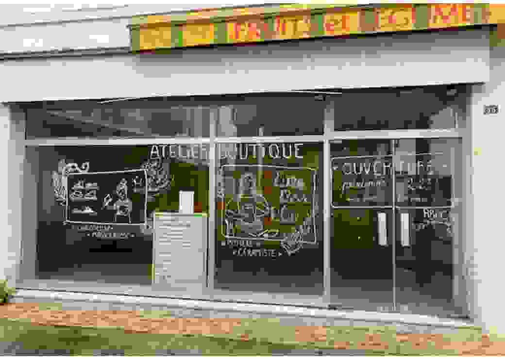 Photo d'une vitrine sur laquelle on peut lire "atelier boutique", accompagné de dessins