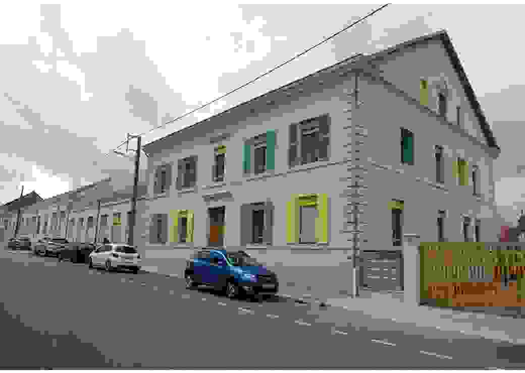 depuis la rue, photo d'une bâtisse de deux étages aux volets peints en vert, jaune et bleu
