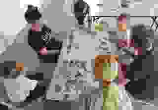 Vue du dessus, une table sur laquelle sont posés une carte et des photos. 5 personnes, enfants et adultes, se tiennent autour de la table
