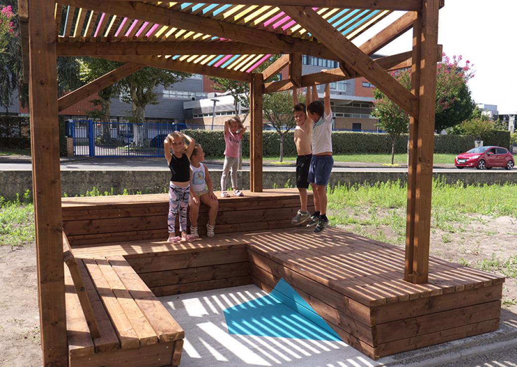 Des enfants jouent sous une ombrière au toit coloré