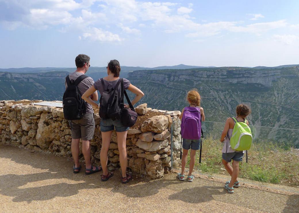 Vue de dos d'une famille au sommet d'une colline, en train de regarder le paysage du Grand Cirque de Navacelles