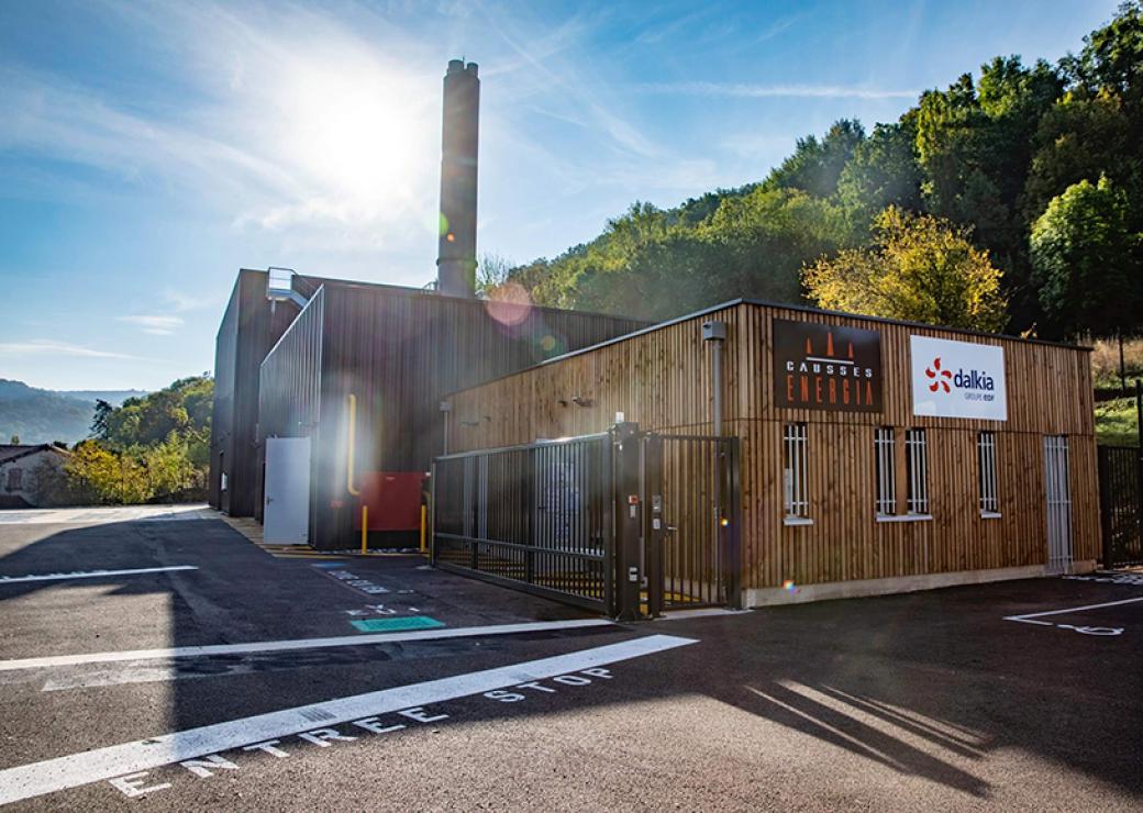 Photo d'un bâtiment industriel dont la façade est bardée de bois. Une grande cheminée s'en élance.