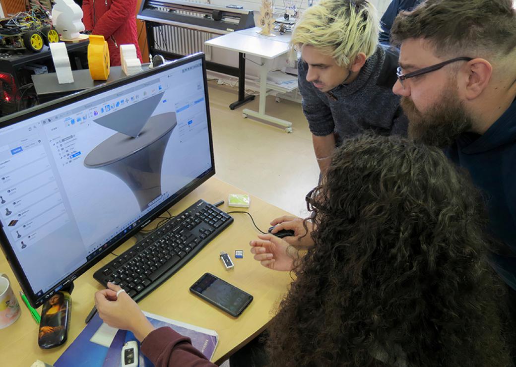 Trois personnes regardent un graphique en 3D sur un écran d'ordinateur