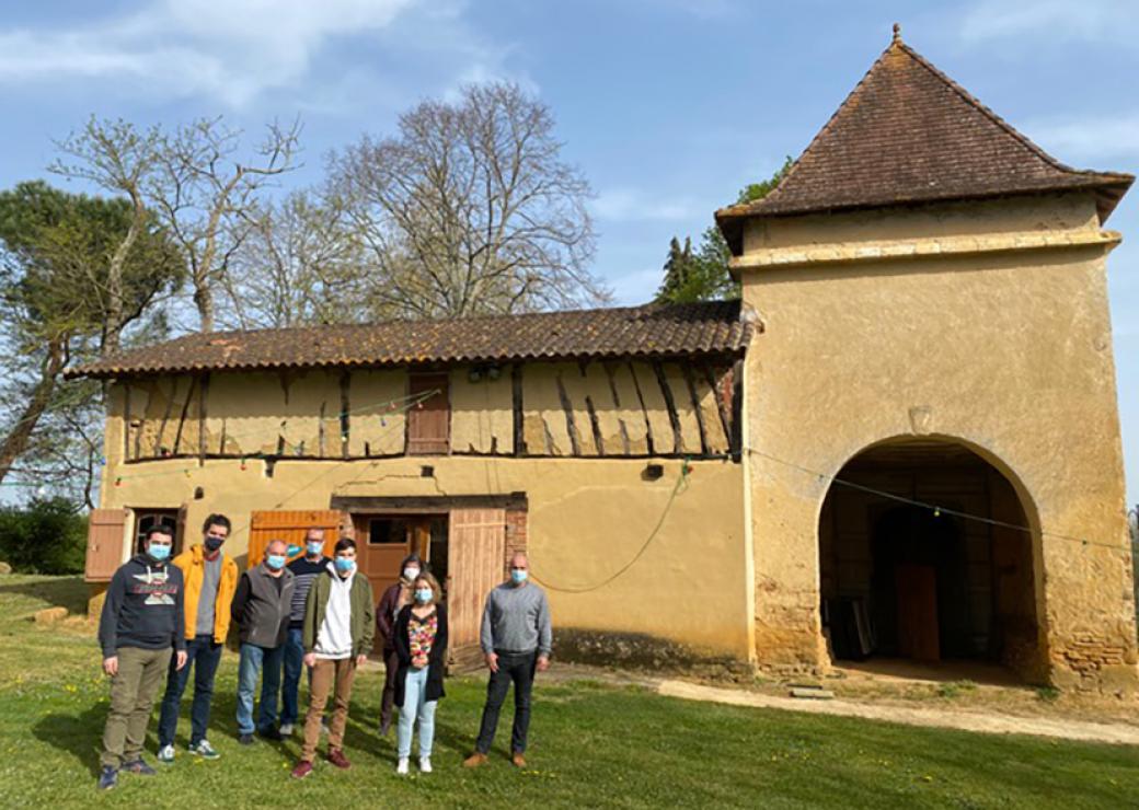 devant une grange, un groupe de 8 personnes masquées pose pour le photographe