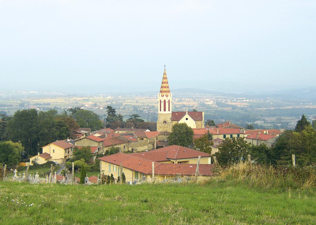 Vue en surplomb d'un village de maisons de pierre, avec en son centre un clocher.