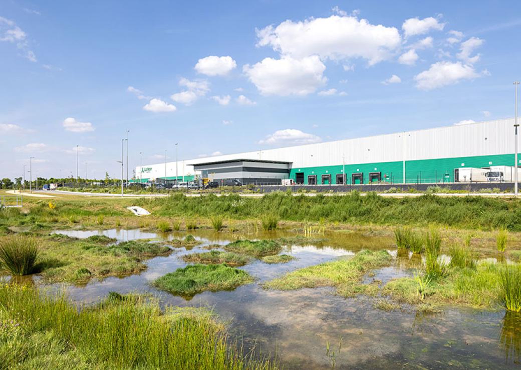 Photo d'un hangar de logistique avec au premier plan, un étang