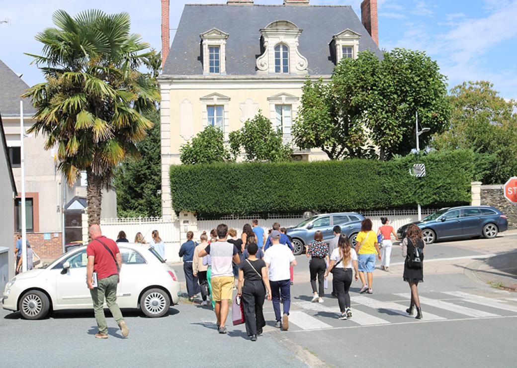 Dans la rue, une vingtaine de personnes marchent. Elles sont de dos