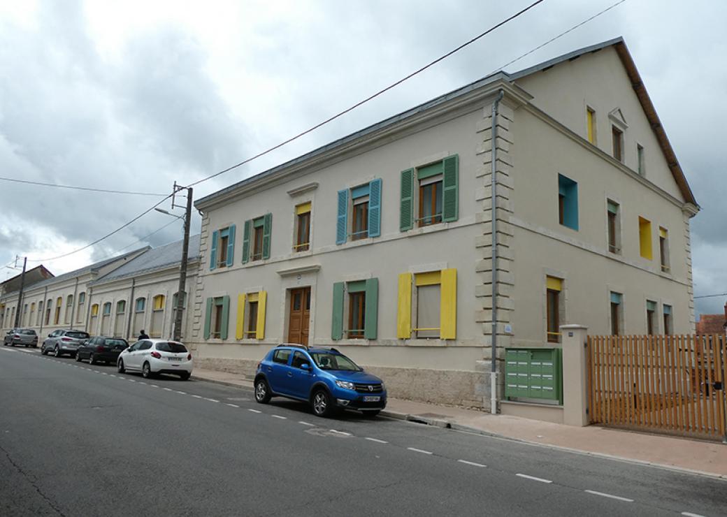 depuis la rue, photo d'une bâtisse de deux étages aux volets peints en vert, jaune et bleu