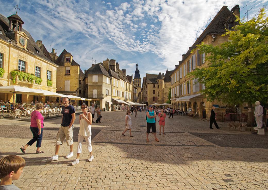 En été, un centre historique, des personnes en tenue estivale déambulent