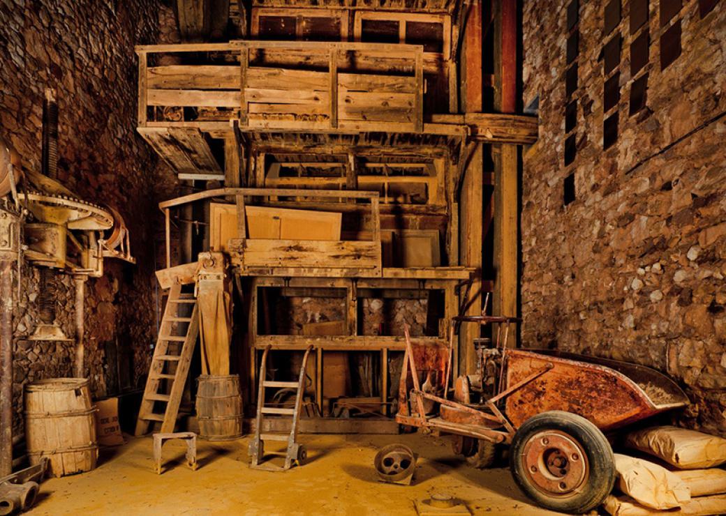 L'intérieur d'un atelier ancien dont le sol est recouvert d'une fine poudre ocre