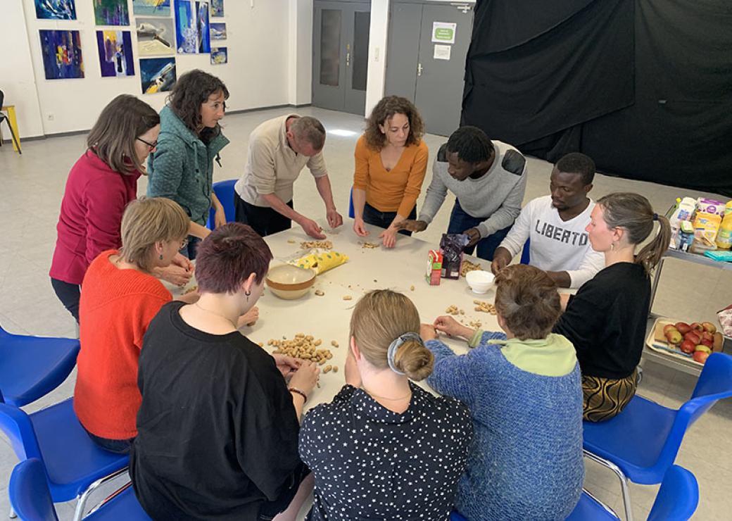 Une dizaine de personnes se tiennent autour d'une table, épluchant des fruits ou des légumes