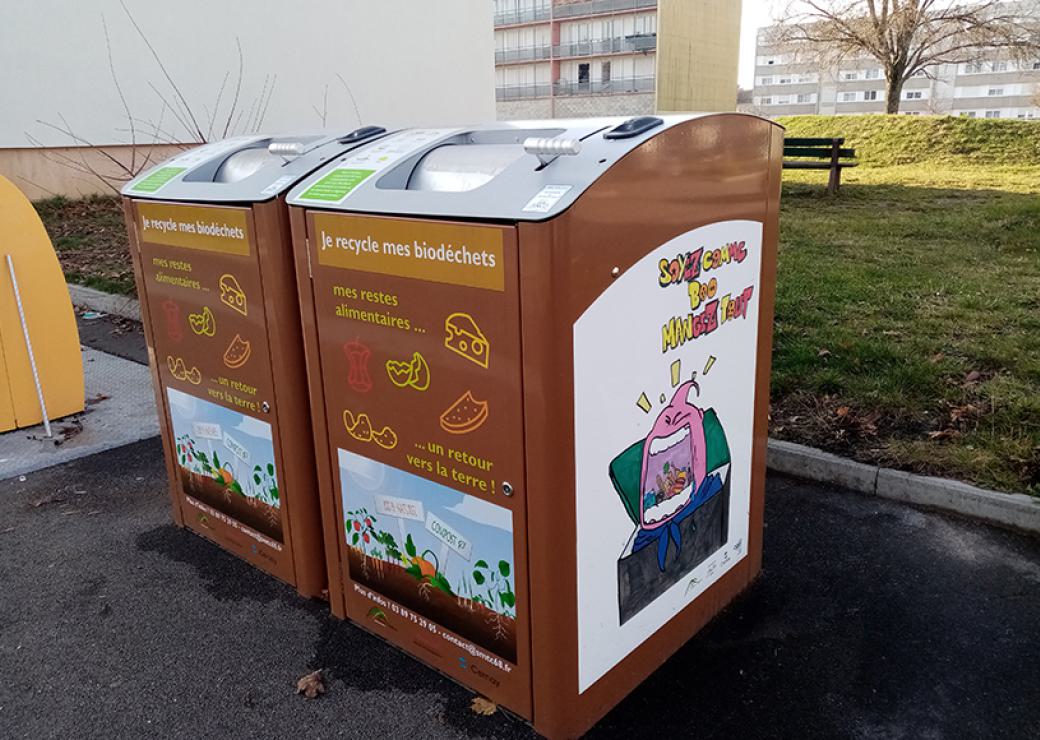 Bacs sur lesquels on peut lire "je recyle mes biodéchets", installés en pied d'immeuble