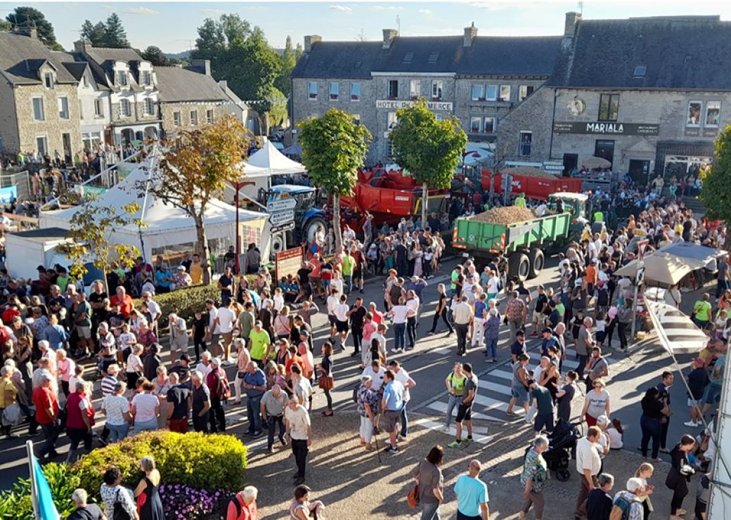 Une place de village vue du ciel, un jour de grande activité, avec beaucoup de monde dans la rue