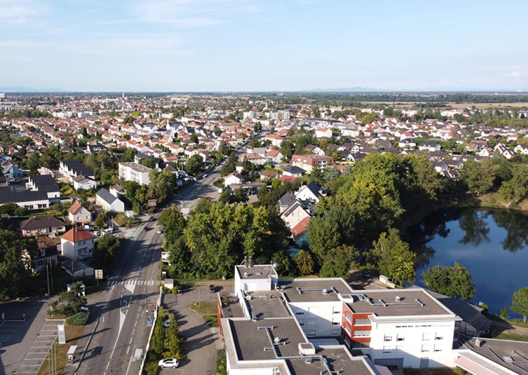 Vue aérienne d'une petite ville. Au premier plan, un petit plan d'eau
