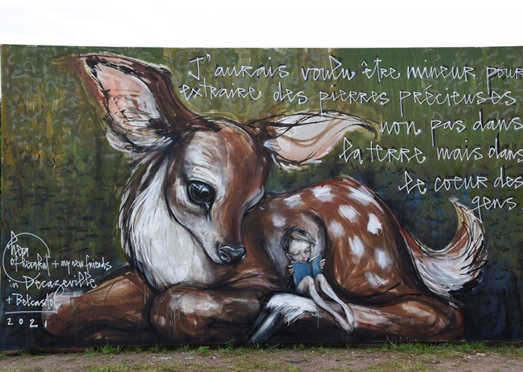 Peinture murale figurant un enfant lisant adossé à une faon. Sur le côté on peut lire "jaurais voulu être mineur pour extraire des pierres précieuses non des mines mais du cœur des gens"
