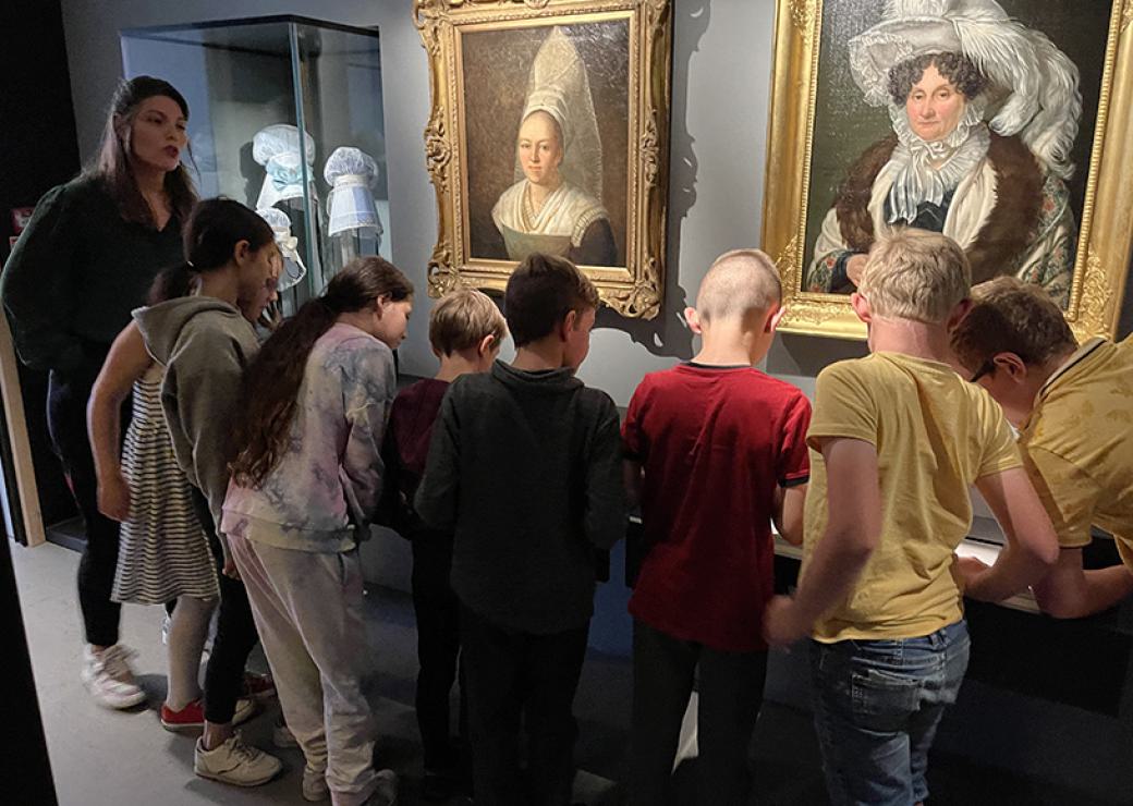 Un groupe d'enfants devant deux tableaux - portraits de femme