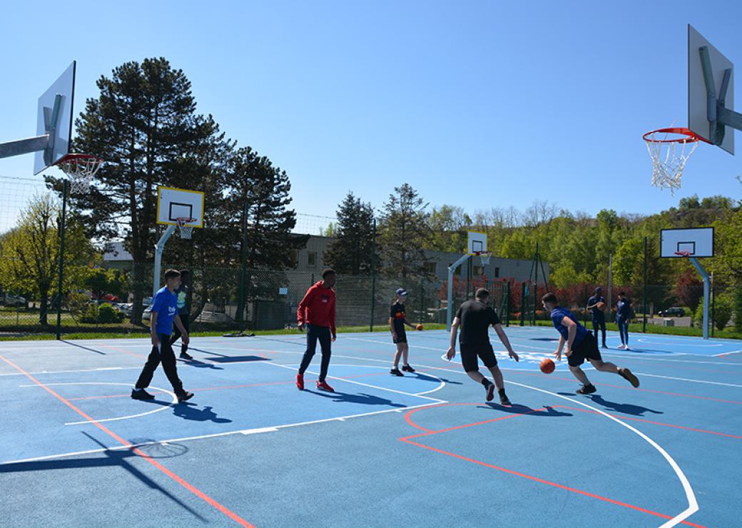 Des jeunes jouent sur un terrain de basket bleu