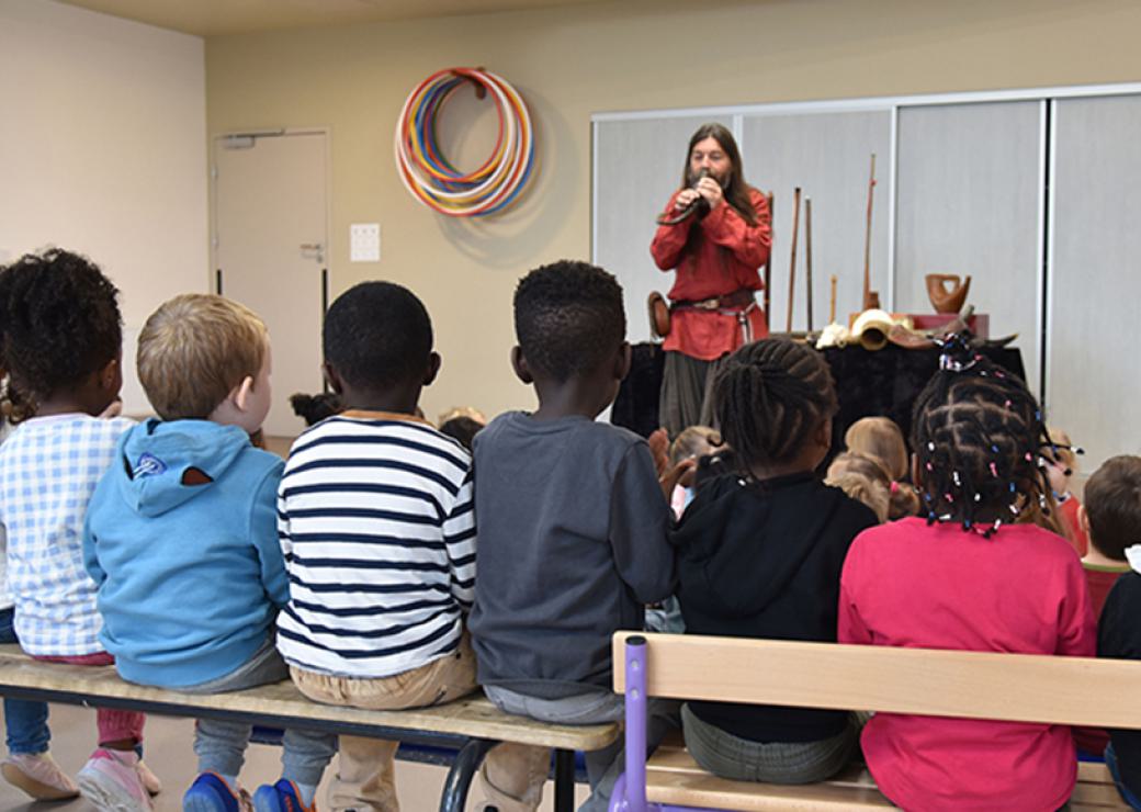 Des enfants, vus de dos, assistent à une représentation