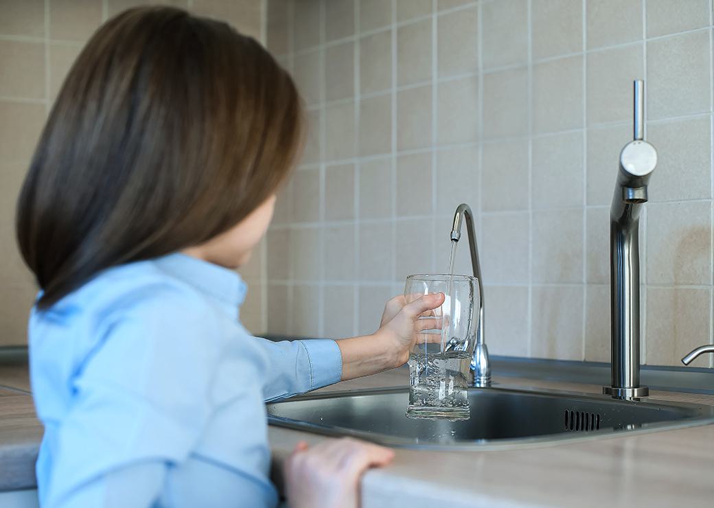 un enfant se sert un verre d'eau au robinet 