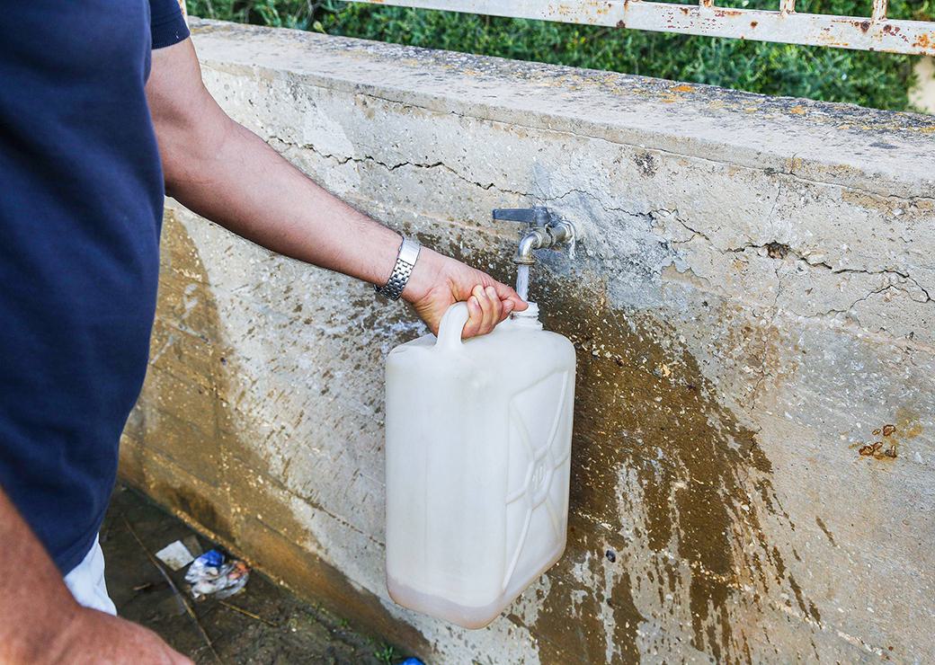 un homme remplit un bidon d'eau