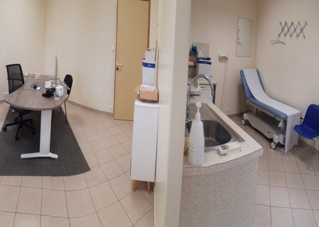 Vue intérieure d'un cabinet médical, avec table d'auscultation, chaise, bureau