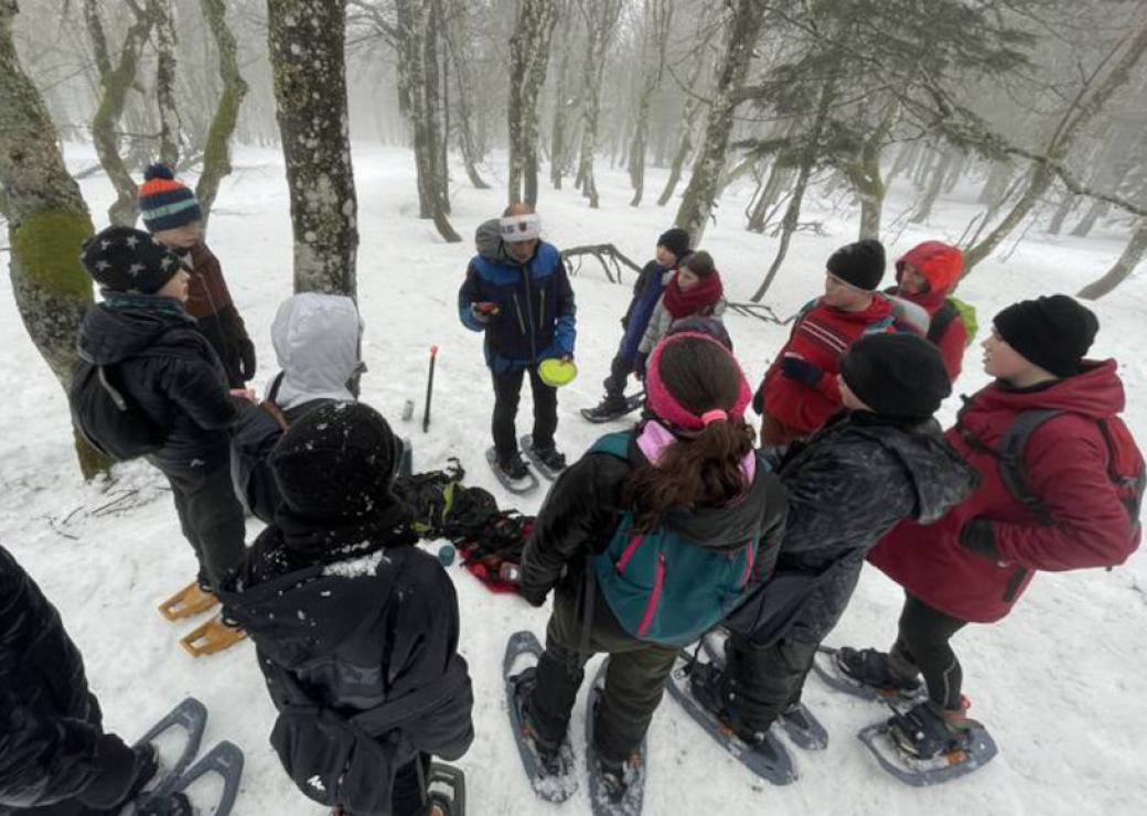 Des enfants autour d'un homme dans une forêt sous la neige