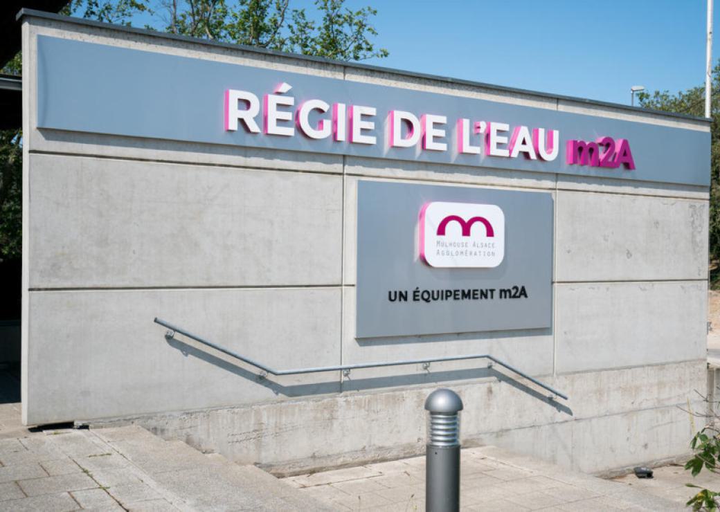 Sur un mur de béton, on peut lire "régie de l'eau m2A"