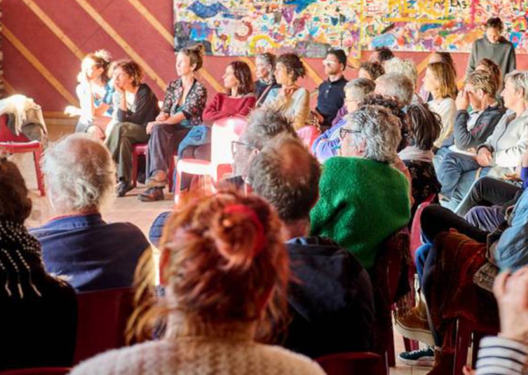 Des personnes assises en cercle assiste à quelque chose qui ne figure pas dans l'image