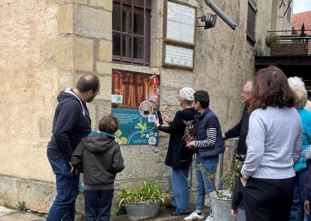 Des personnes regardent un panneau posé sur le mur d'une maison