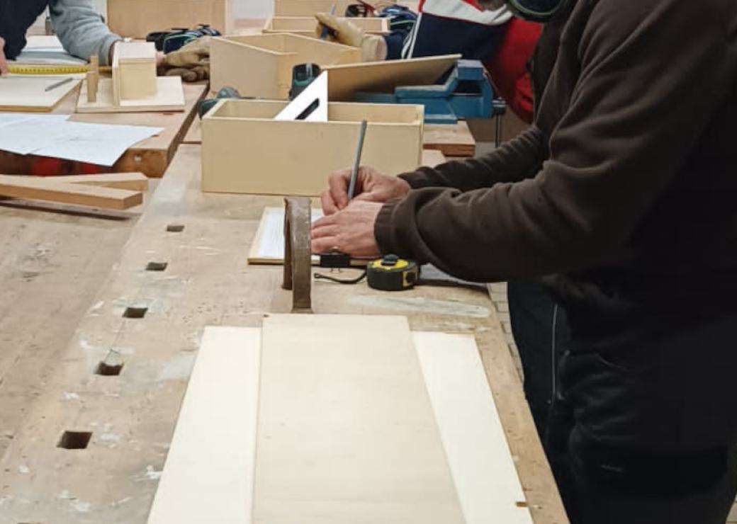 Plan resserré sur des main qui dessinent ou prennent des mesures sur du bois