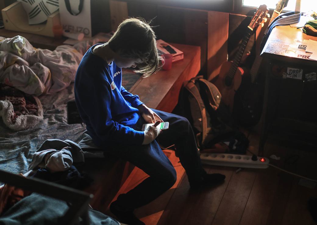 un enfant dans sa chambre regardant son télephone