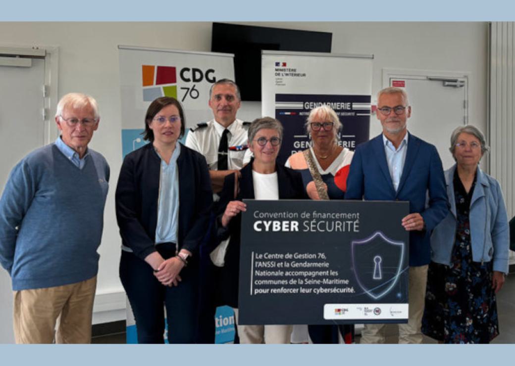 Des personnes se tiennent debout autour d'un panneau sur lequel on peut lire "convention financement cybersécurité"