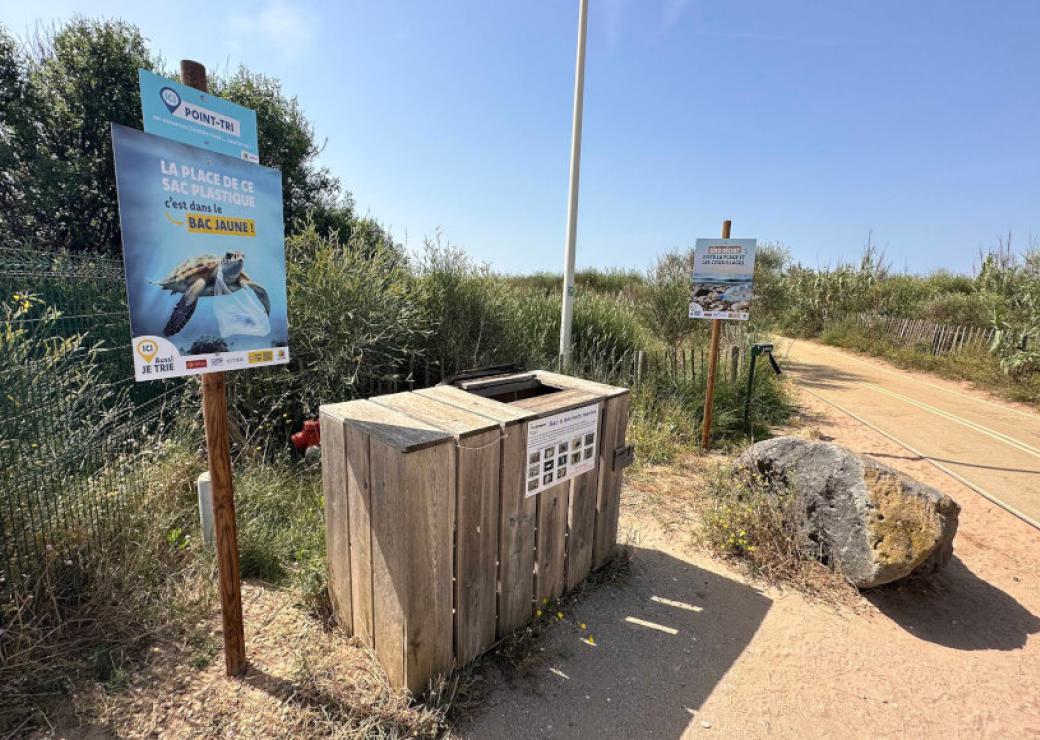 Des conteneurs bardés de bois à côté d'un chemin entre deux dunes