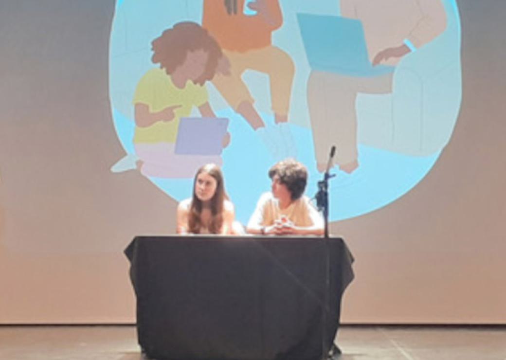 Deux enfants sur une scène avec un visuel relatif aux écrans derrière eux