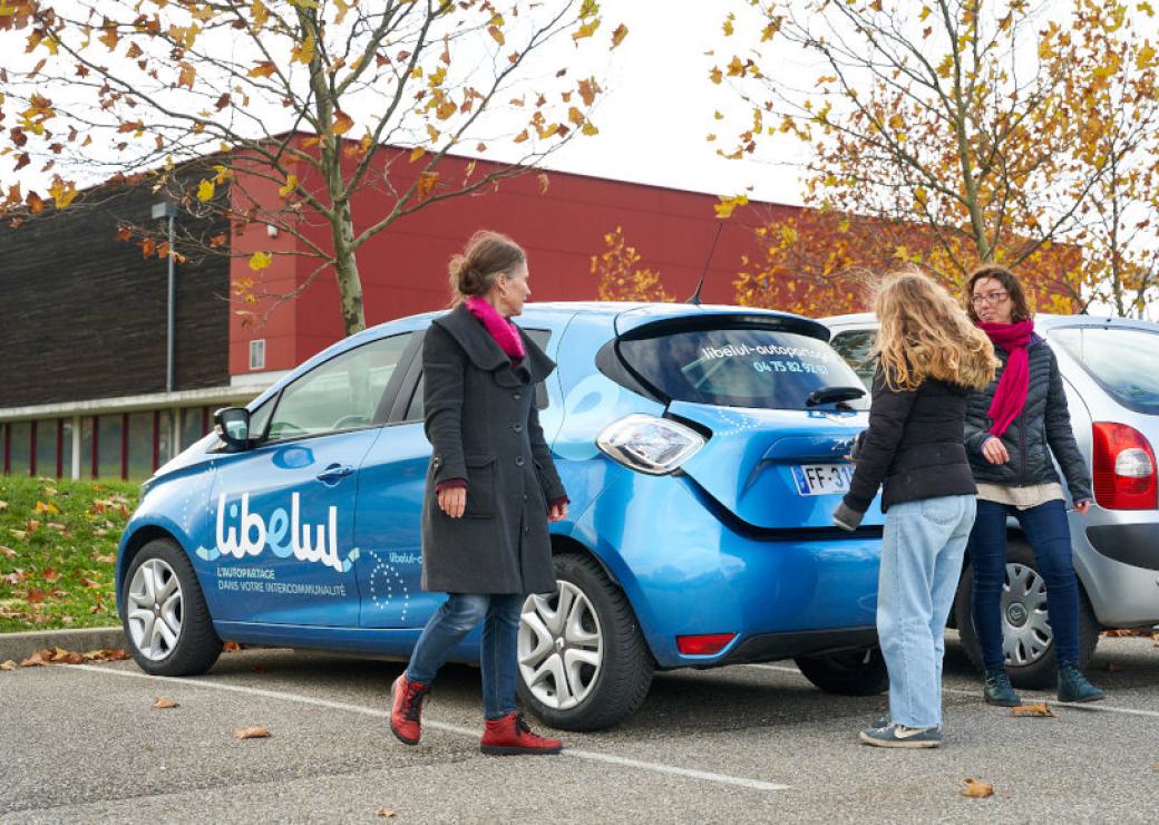 Trois personnes autour d'une voiture bleue sur laquelle on peut lire "Libelul"