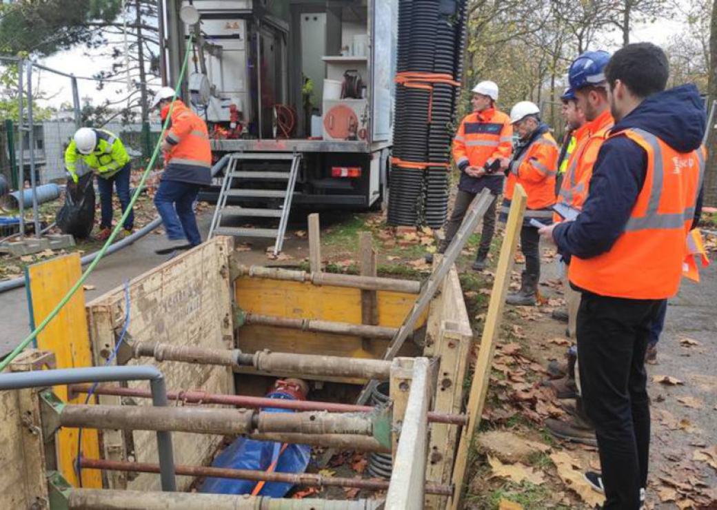 Des hommes en tenue de chantier se tiennent autour d'un trou