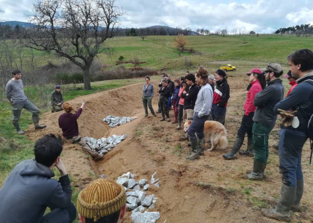 Un groupe de personne se tient sur le bord d'un fossé fraîchement creusé