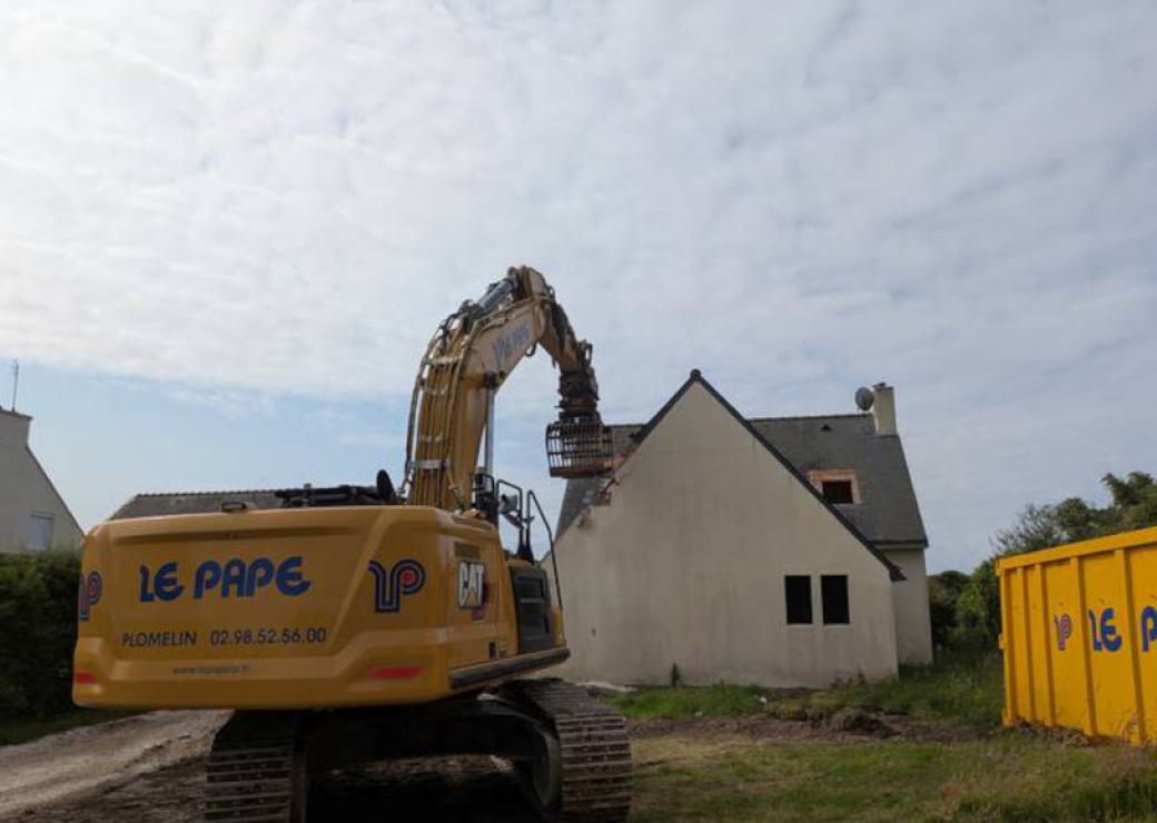 Un tractopelle devant une maison