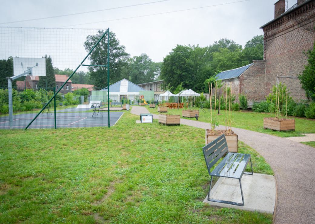 Un jardin avec un terrain de basket et des bacs de plantation