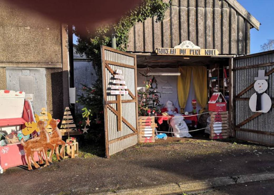 Une grange portes ouvertes, avec des décoration de noël et un panneau "bureau du père noël"