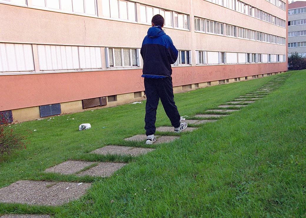 Un adolescent marche dans une cité hlm 
