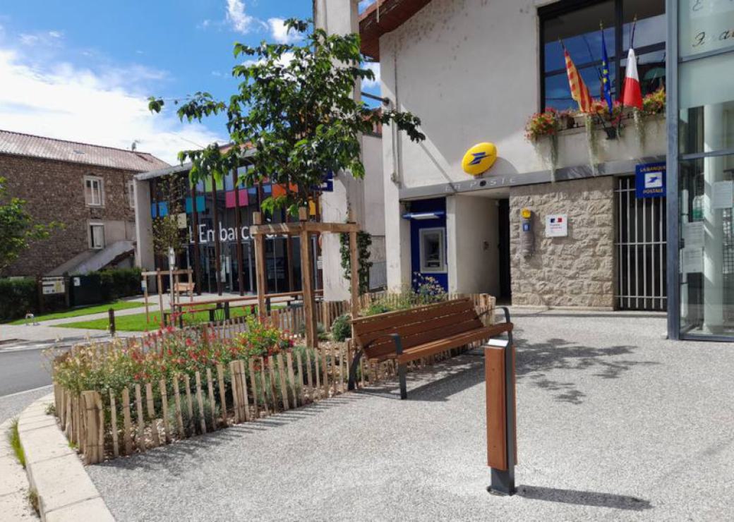 Vue d'une placette équipée d'un banc, devant un bureau de poste