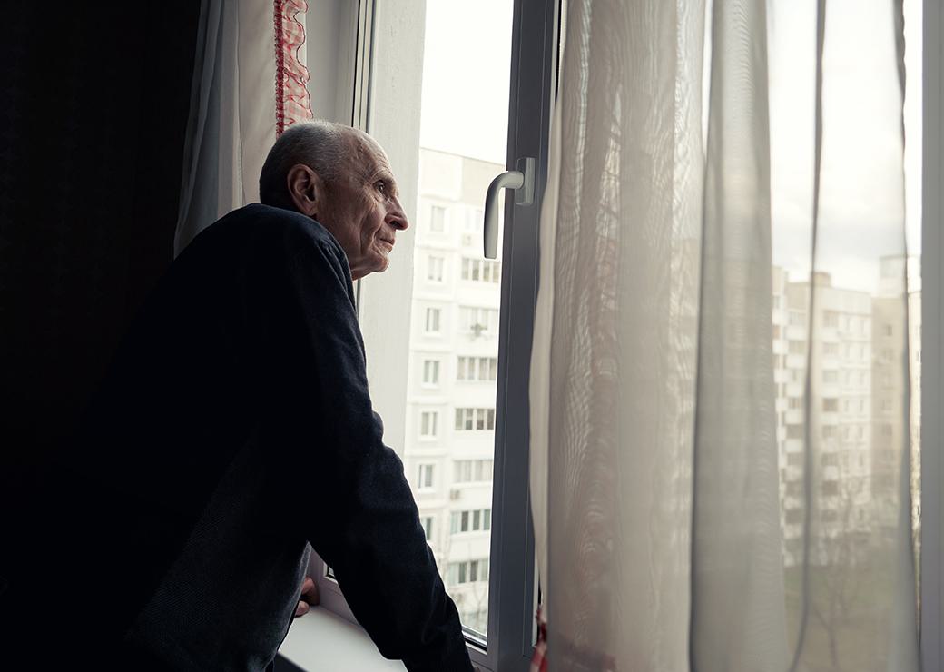 Un homme agé regarde par la fenetre 