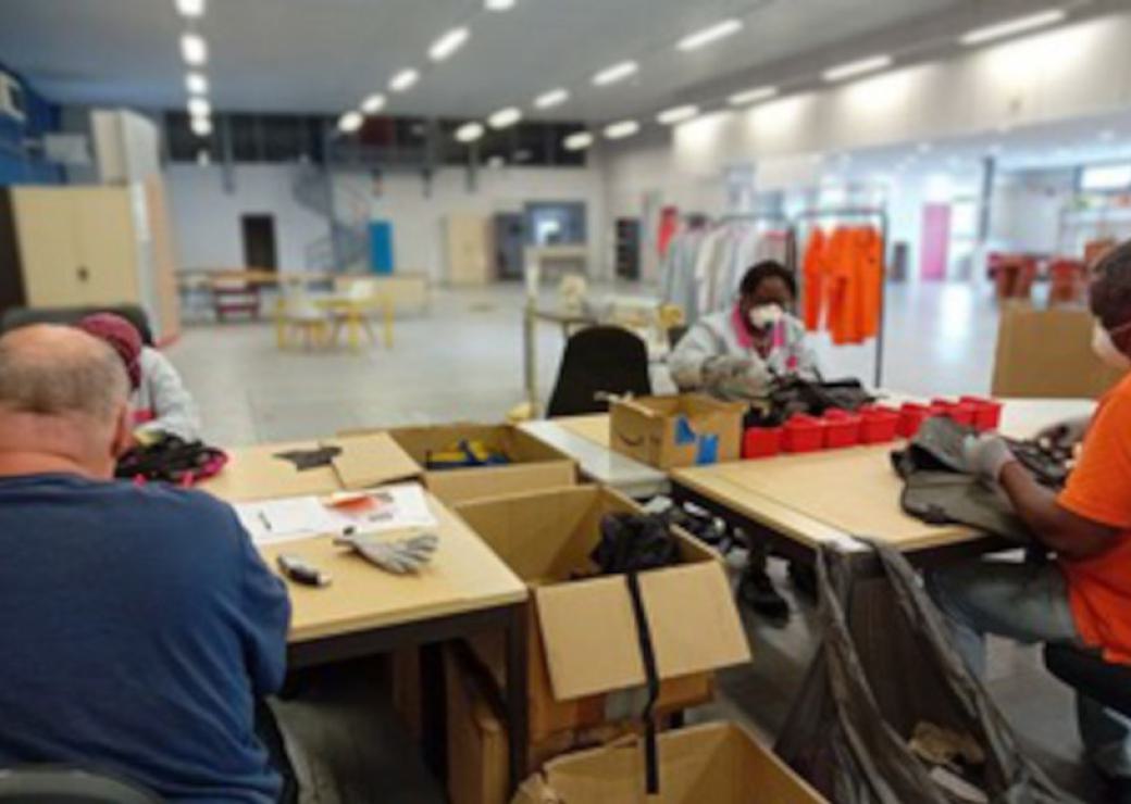 Des personnes dans un atelier, assises face à des tables sur lesquelles sont posées leur ouvrage