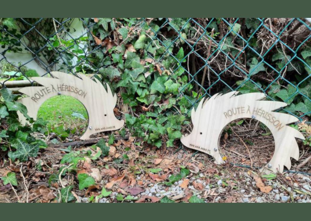 Des cadres de bois en forme de silhouette de hérissons, perçée d'un rond au milieu, posées en bas de grillage