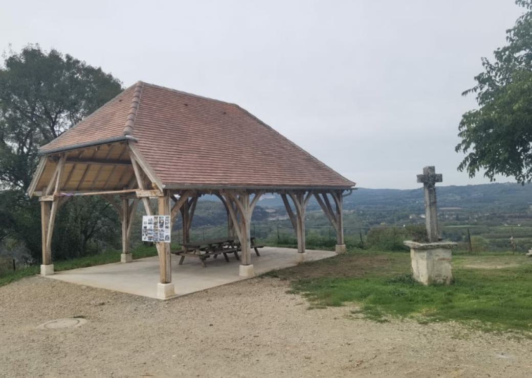 Une halle au toit de tuiles, point de vue ouvert sur le paysage, croix de pierre à côté de la halle