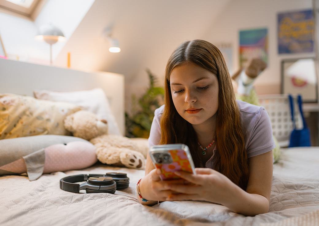 une jeune adolescente dans sa chambre avec son telephone 