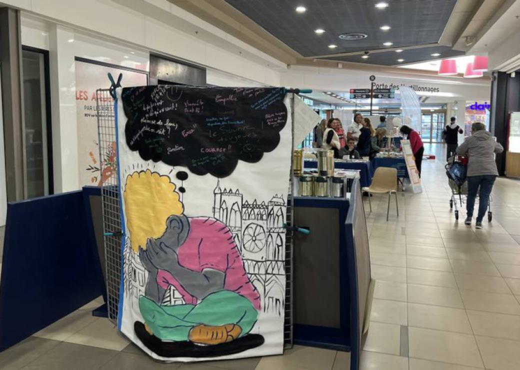 Hall de lieu public, au premier plan un dessin figurant une personne qui tient son visage dans ses mains