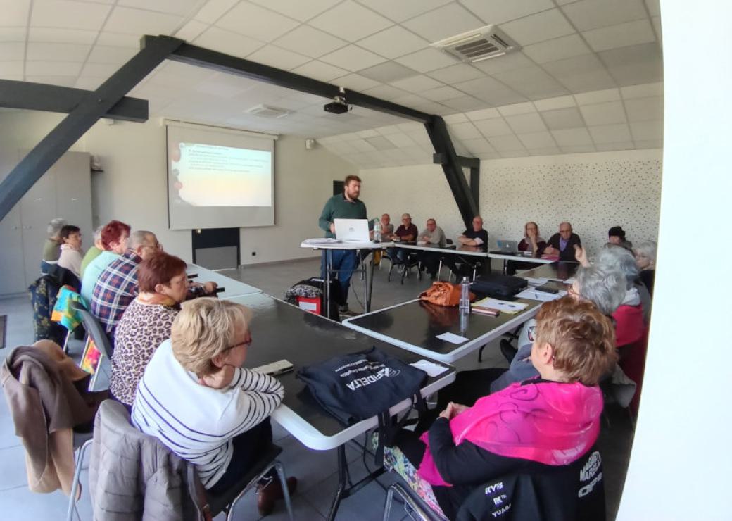 Dansune salle avec des tables installées en U. Une personne debout au milieu, les autres  écoutent. En tout, une quinzaine de personnes